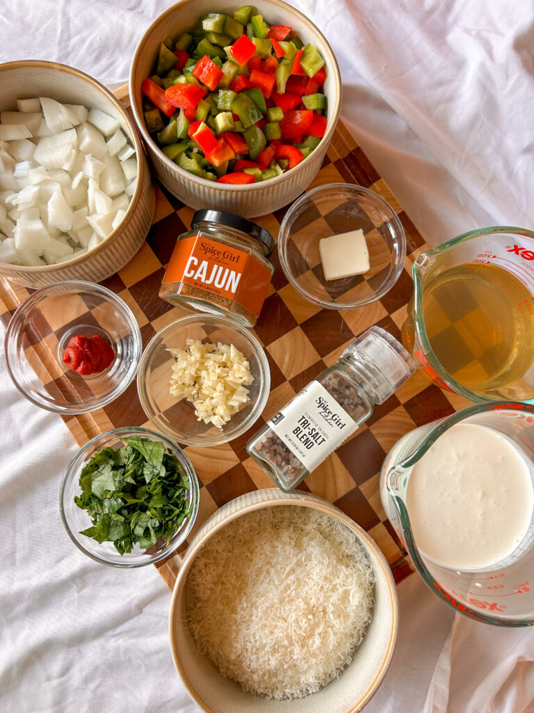 Ingredients for Cajun cream sauce including bell peppers, onion, garlic, Parmesan cheese, heavy cream, and Cajun seasoning