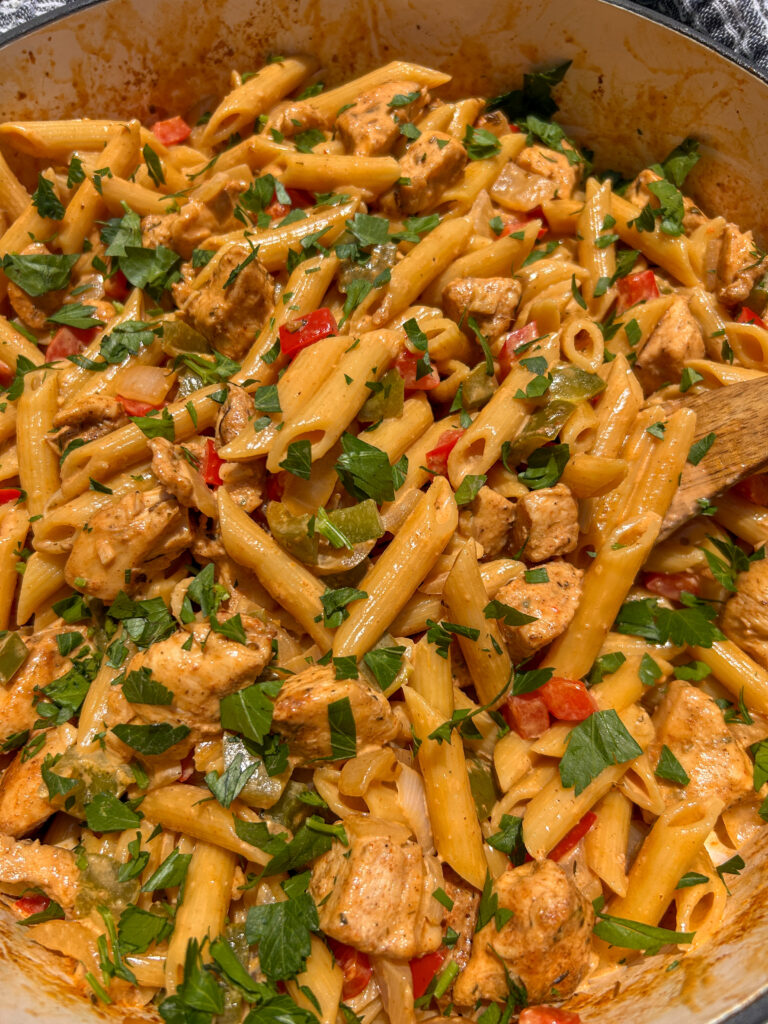 Fresh parsley and Parmesan cheese being added to creamy Cajun chicken pasta