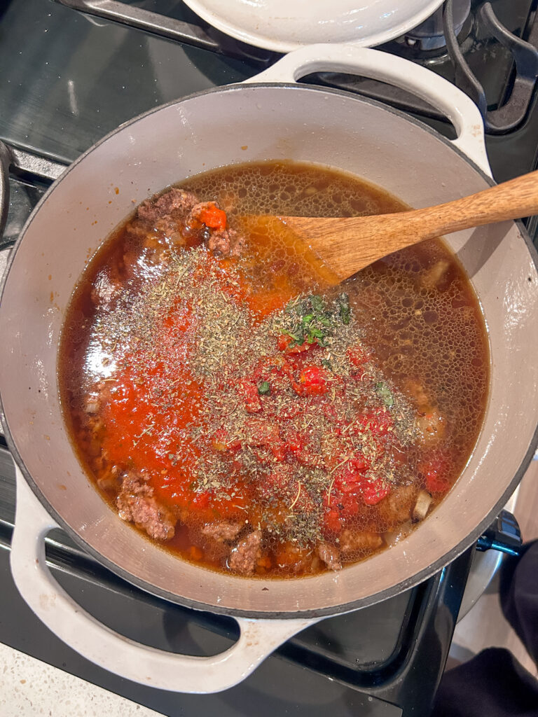 Adding broth and marinara sauce to lasagna soup base