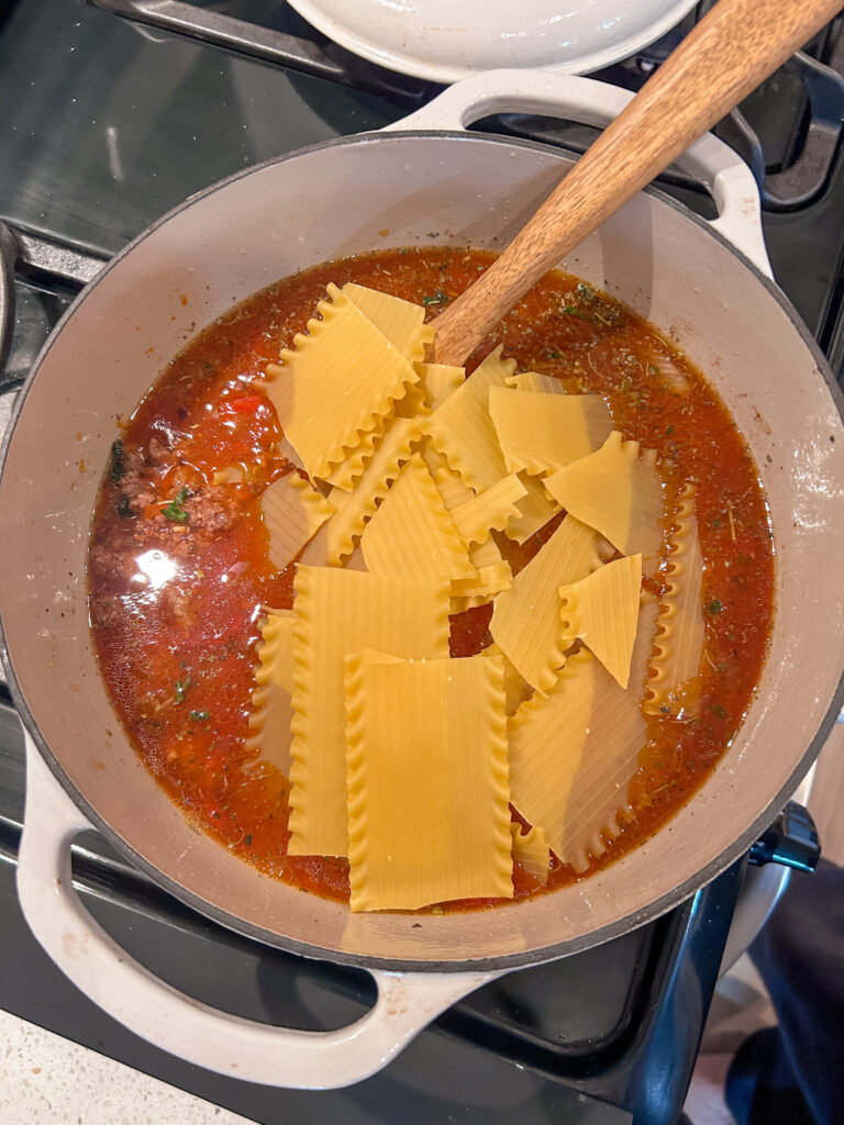 Adding broken lasagna noodles to the soup to simmer