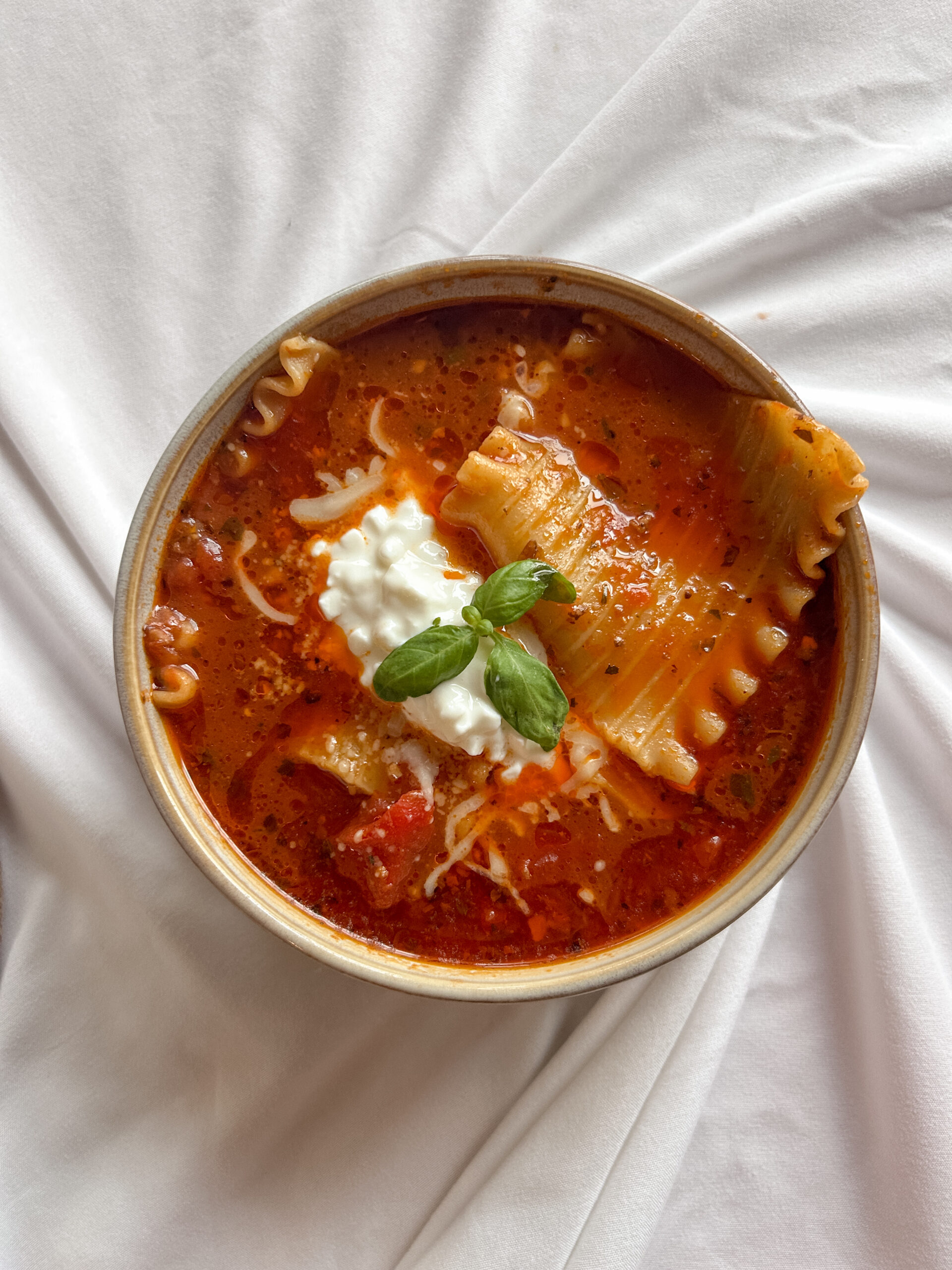 Bowl of lasagna soup topped with ricotta, mozzarella, and parmesan