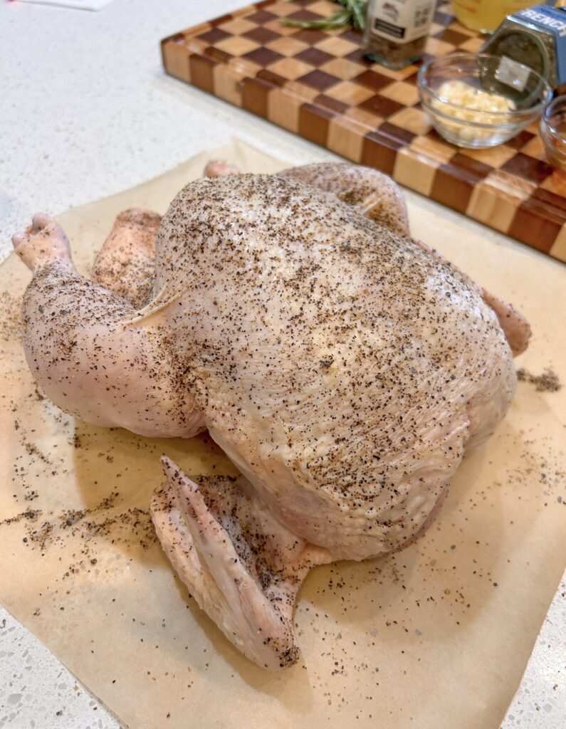 Seasoning a whole chicken with salt and black pepper before pressure cooking
