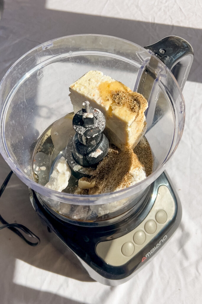 feta and goat cheese in a food processor ready to be blended