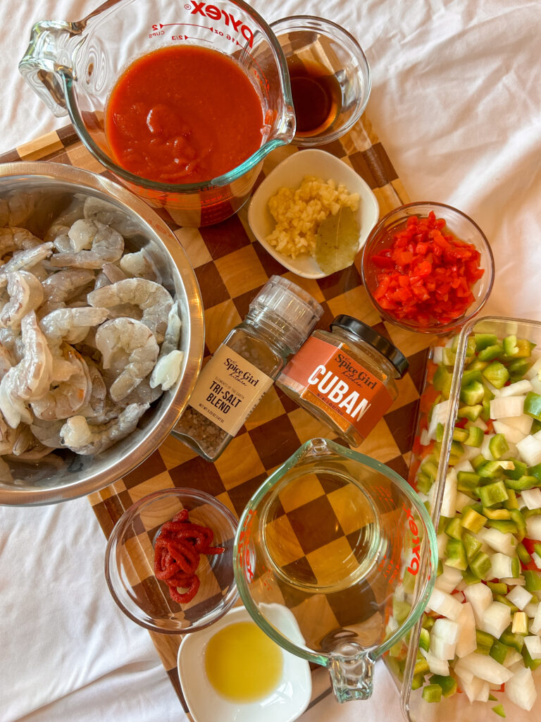 Ingredients needed to make camarones enchilados including shrimp, peppers, tomato sauce, vino seco, and Cuban seasoning