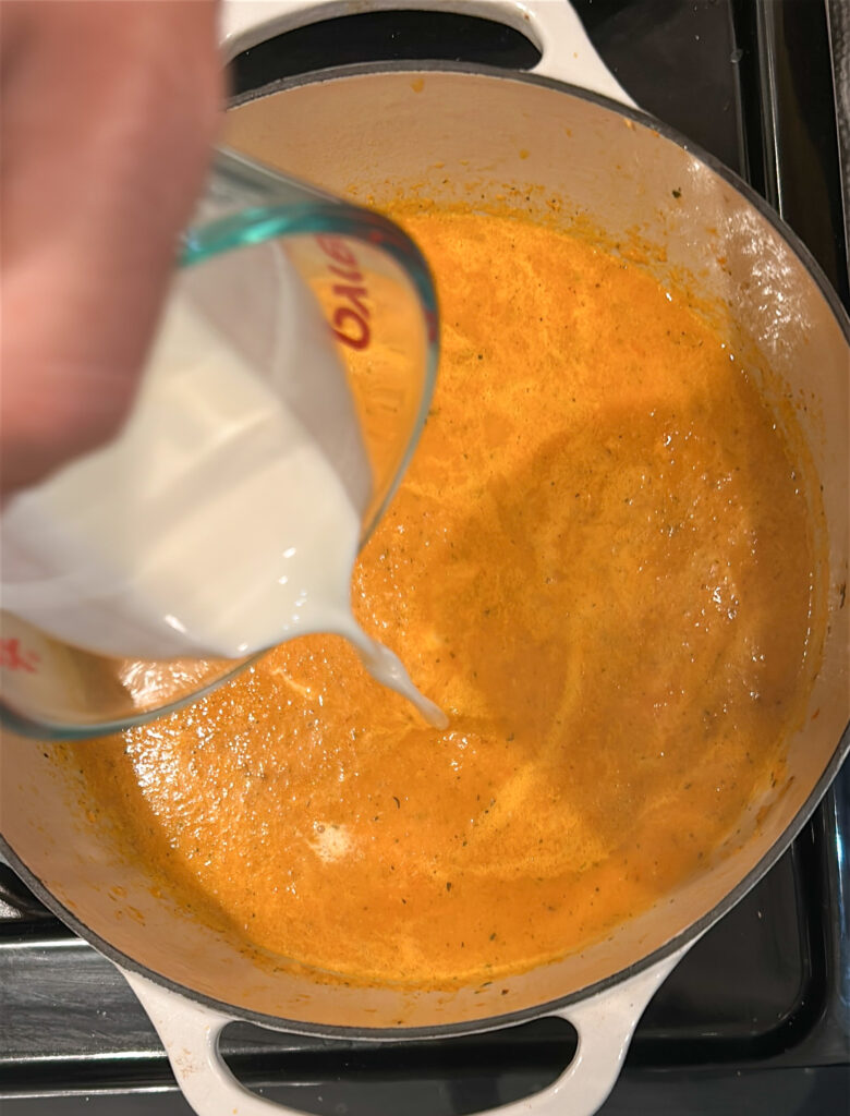 adding cream and lobster meat to bisque