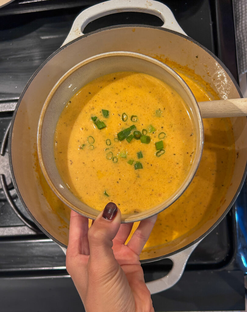 serving lobster bisque with green onion garnish