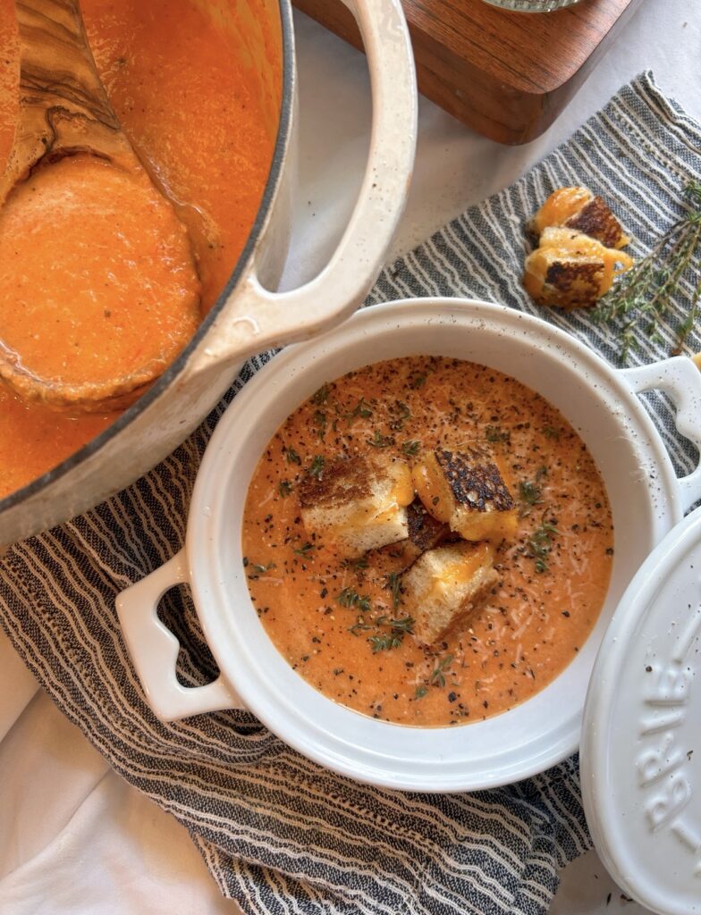 Creamy homemade roasted red pepper and tomato soup finished with shaved Parmesan and black pepper