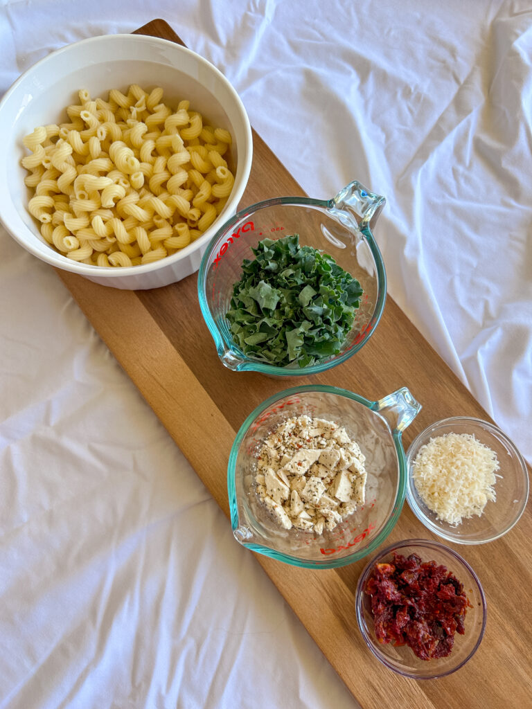 Ingredients for Mediterranean kale pasta salad including pasta, kale, feta, and sun-dried tomatoes