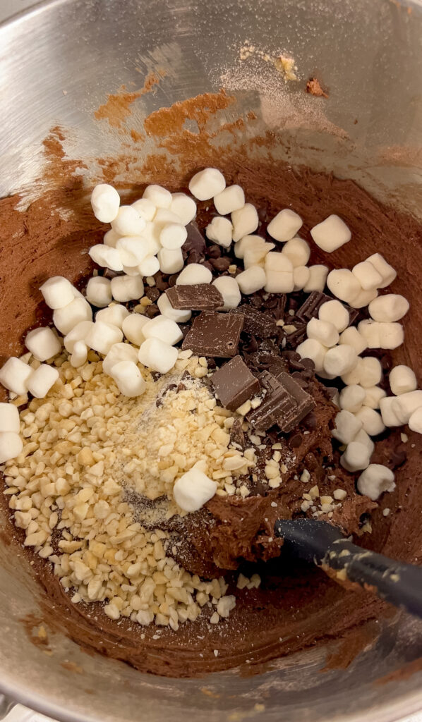 Folding chocolate, nuts, and marshmallows into rocky road cookie dough