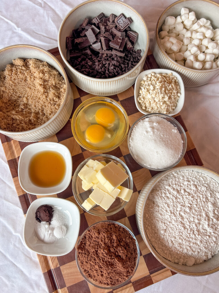 Ingredients for rocky road cookies including chocolate, marshmallows, nuts, and cocoa powder