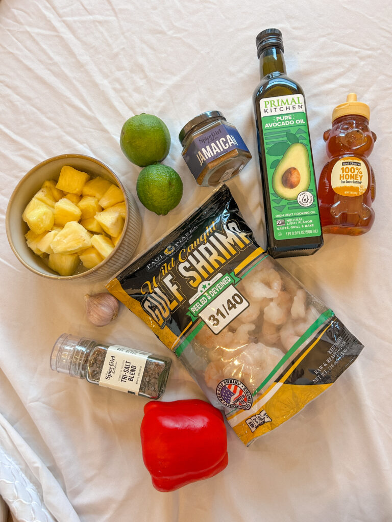 ingredients for shrimp and pineapple skewers including shrimp, pineapple, jerk seasoning, lime, and garlic