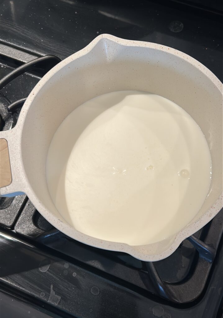 warming milk, cream, and sugar in a saucepan for peppermint hot chocolate
