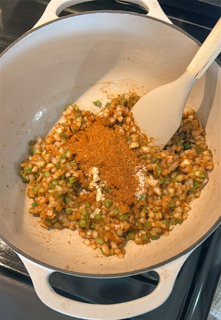 Adding garlic and Cajun seasoning to bloom the spices for shrimp etouffee