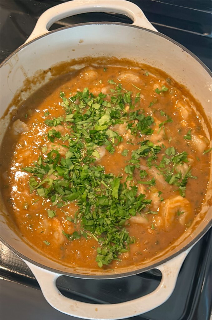 Stirring parsley and green onions into finished shrimp etouffee