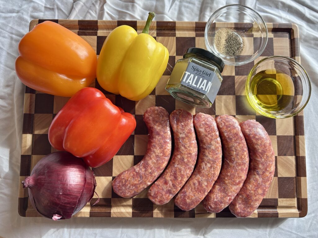 ingredients for sheet pan sausage peppers and onions including Italian sausage, bell peppers, onion, olive oil, and Italian seasoning