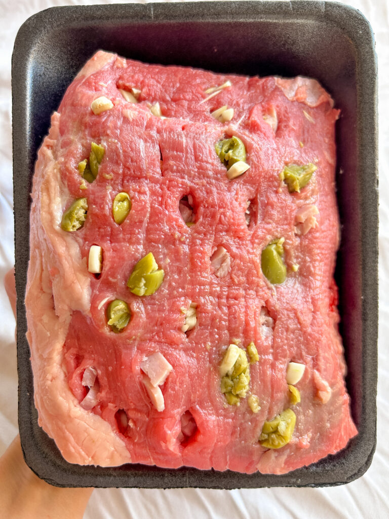 Stuffing eye of round beef for boliche criollo with chorizo, garlic, and olives