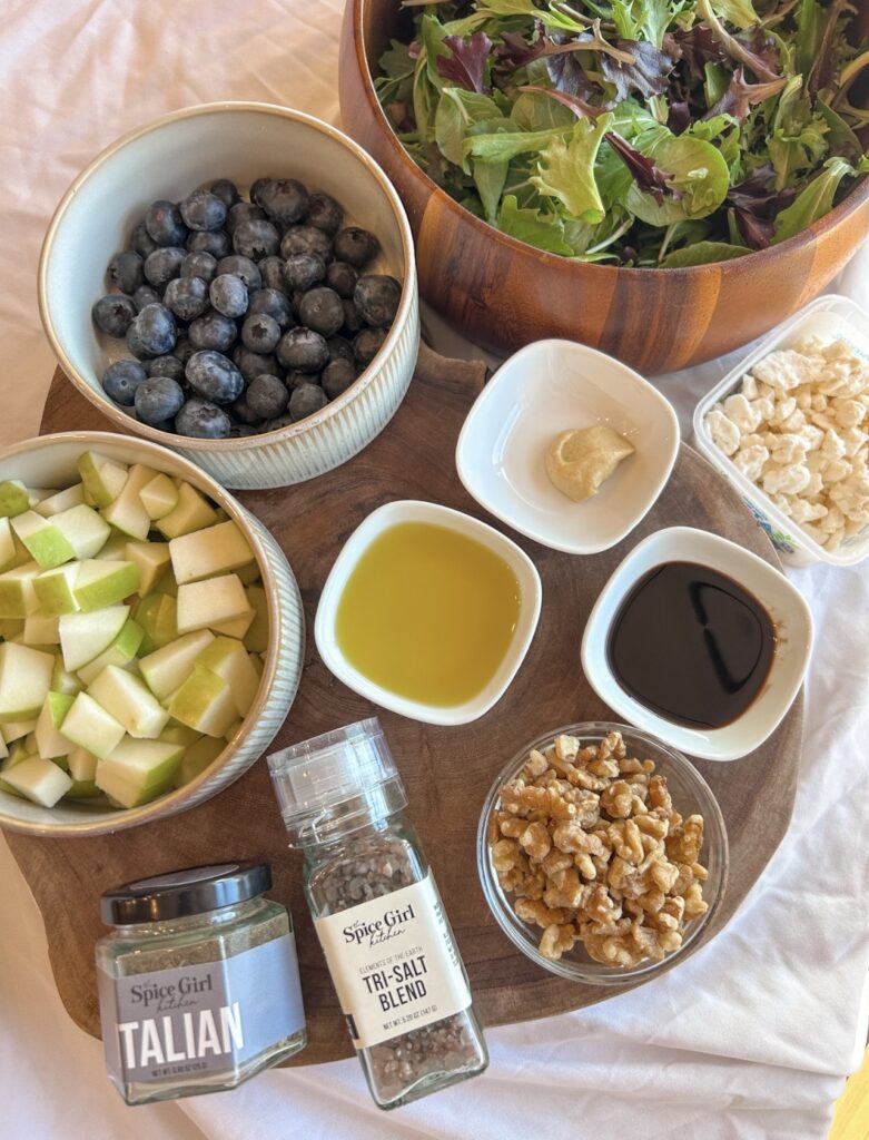 ingredients for blueberry apple salad including mixed greens blueberries apples feta and walnuts