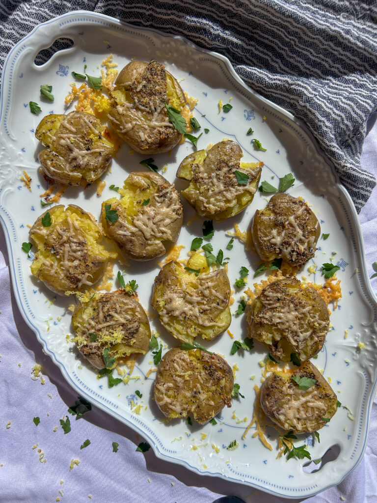 garlic parmesan smashed potatoes served with parsley and lemon zest