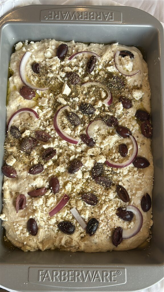Greek focaccia topped with feta and olives before baking