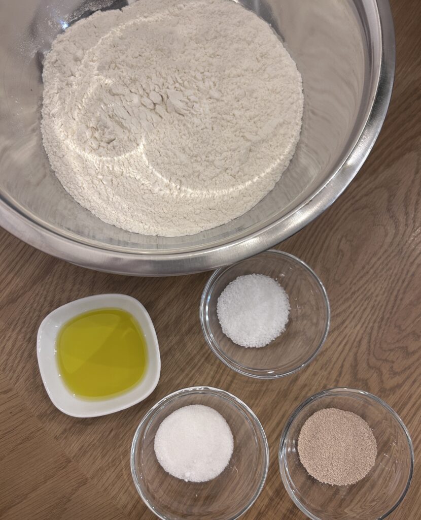 Ingredients for Greek focaccia dough including bread flour, yeast, olive oil, and water