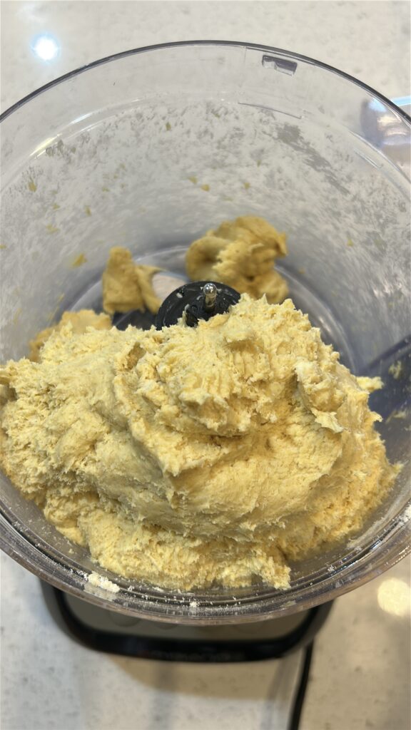 Adding ice water to Jamaican meat pie dough until large clumps form