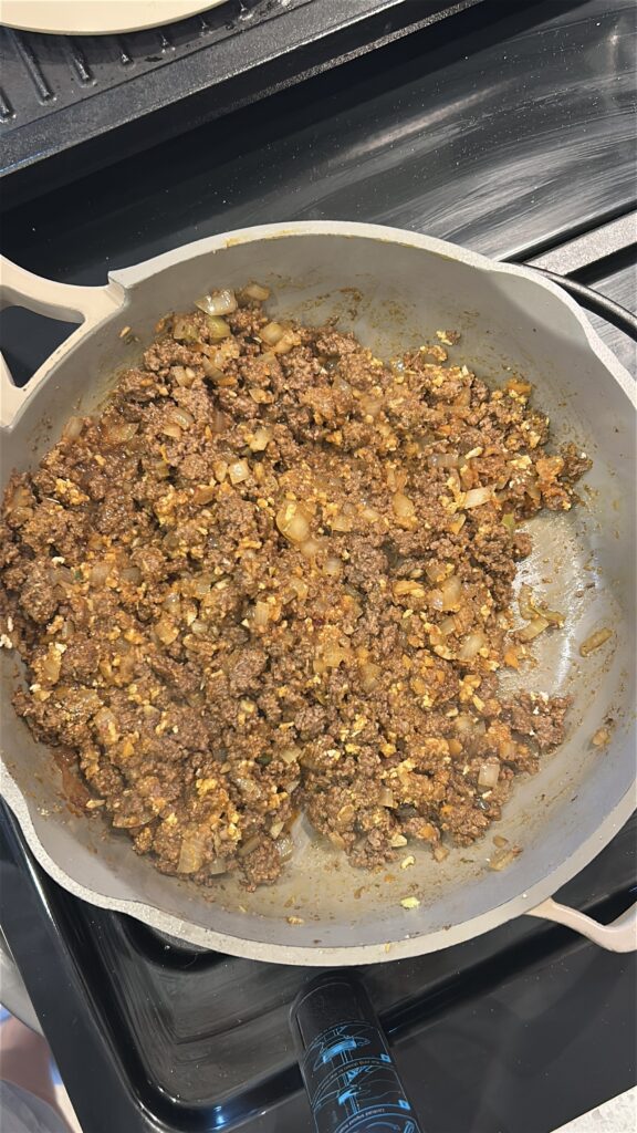 Adding breadcrumbs to bind Jamaican meat pie filling