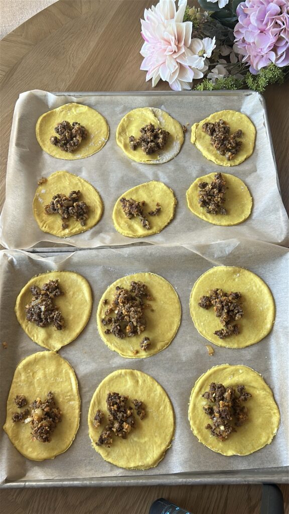 Adding beef filling to Jamaican meat pie pastry circle