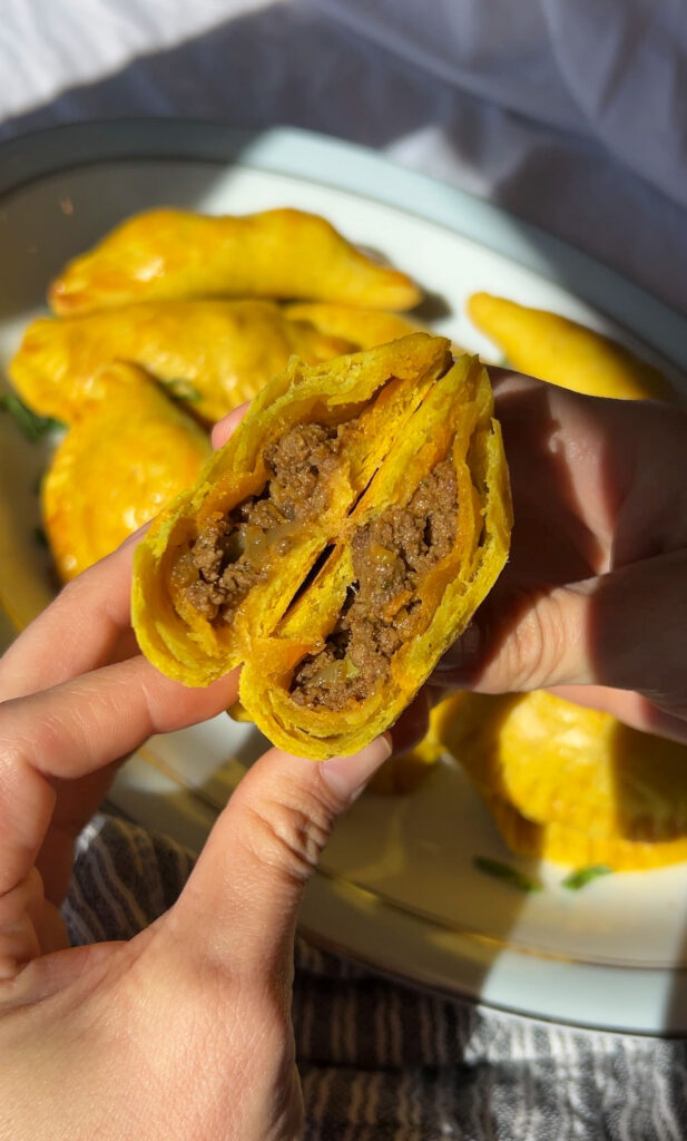 Close up inside of Jamaican meat pie showing juicy beef filling and flaky pastry layers