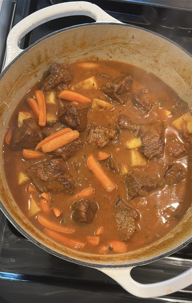 Adding potatoes and vegetables to carne guisada stew