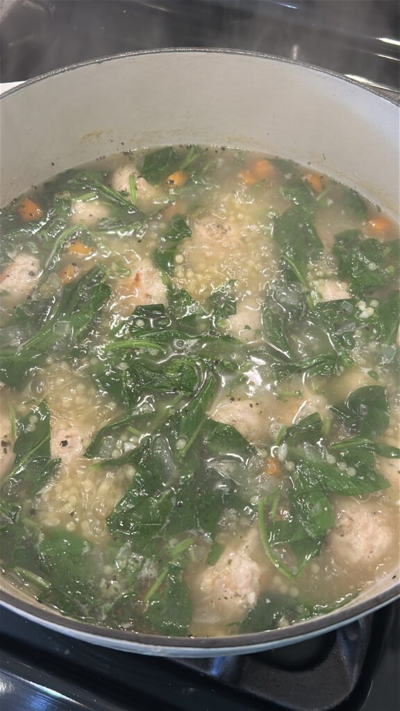 adding spinach and pasta to italian wedding soup