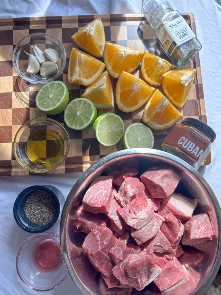 Ingredients for carne guisada marinade including chuck roast, citrus, garlic, and Cuban seasoning