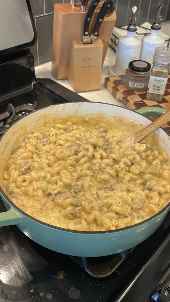 combining pasta, cheese sauce and taco beef for taco mac and cheese