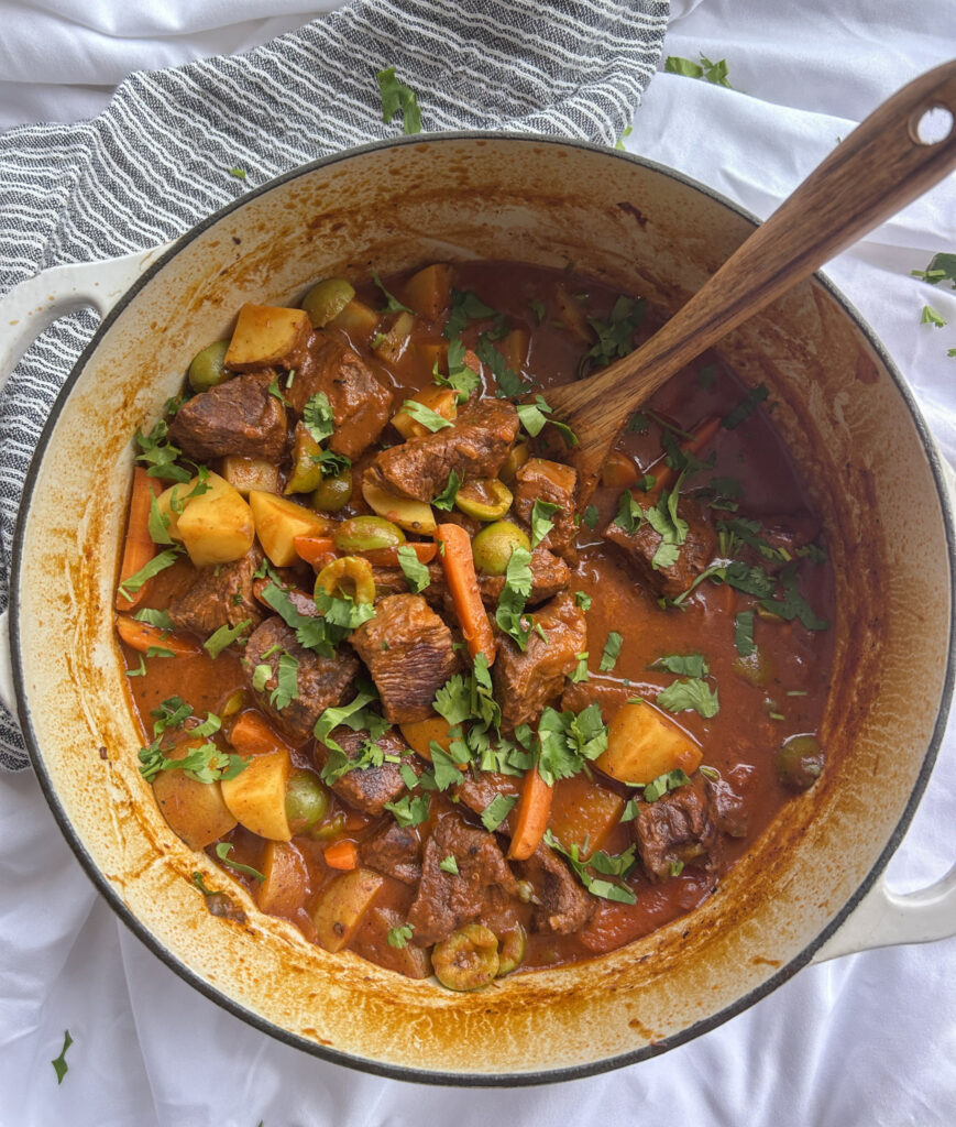 Garnishing Cuban carne guisada with cilantro