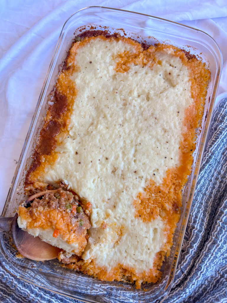 Serving shepherd’s pie with a wooden spoon from baking dish