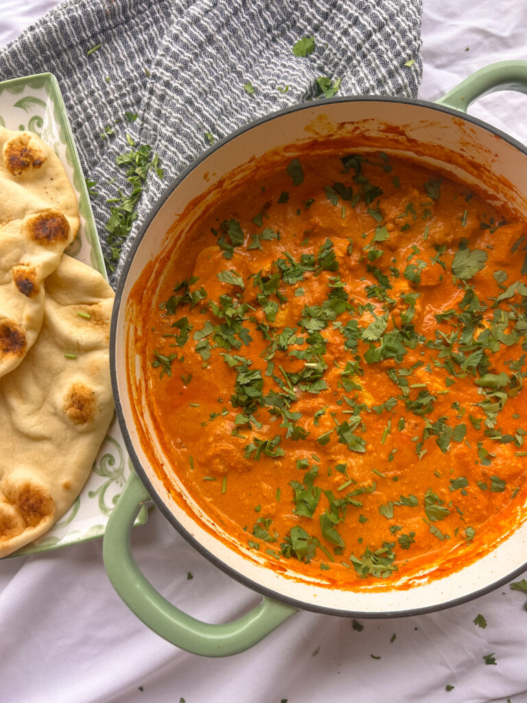Chicken tikka masala served with naan and garnished with cilantro