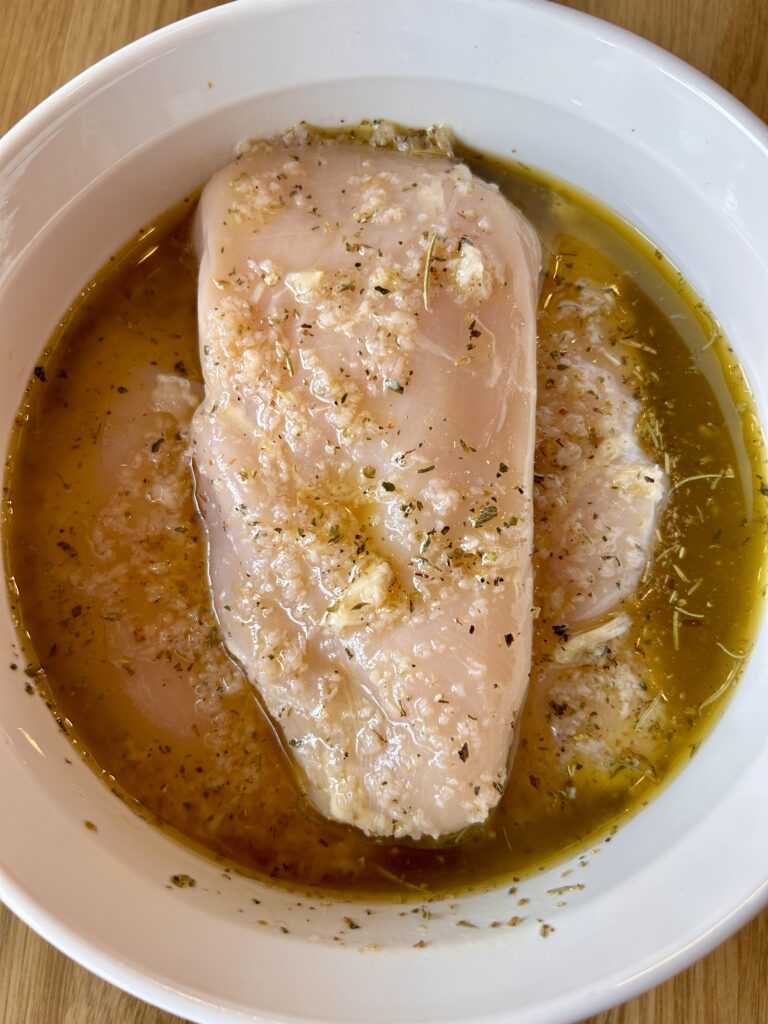 Chicken marinating in Italian chicken marinade with herbs and garlic
