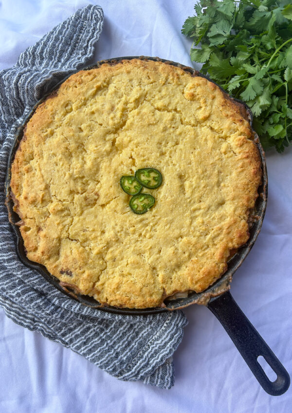 mexican cornbread casserole in cast iron skillet with ground beef and cornbread topping