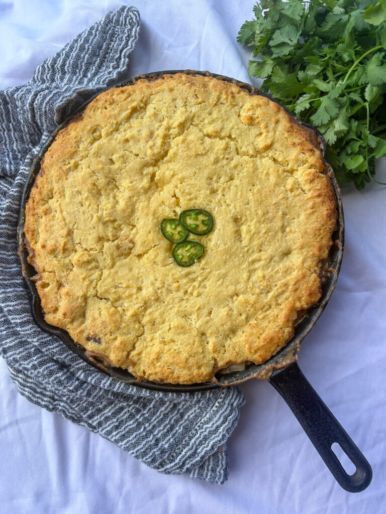 mexican cornbread casserole in cast iron skillet with ground beef and cornbread topping