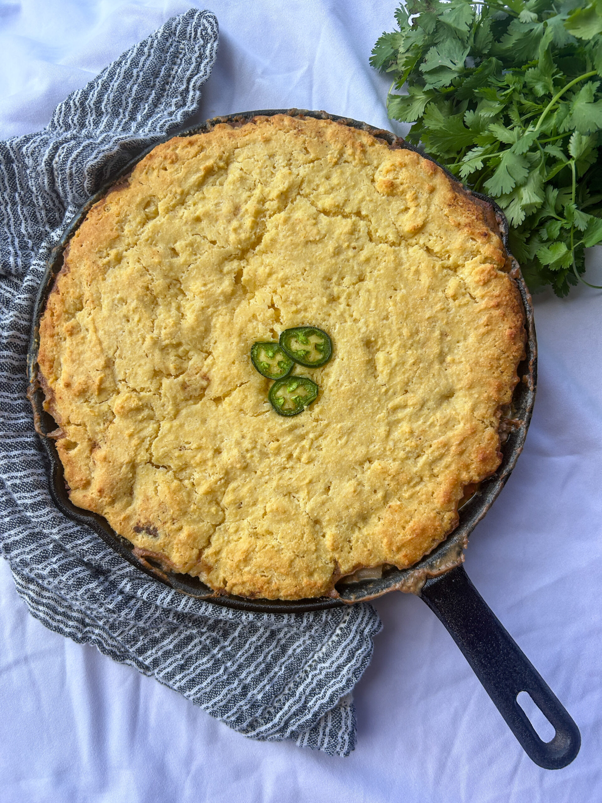 mexican cornbread casserole in cast iron skillet with ground beef and cornbread topping