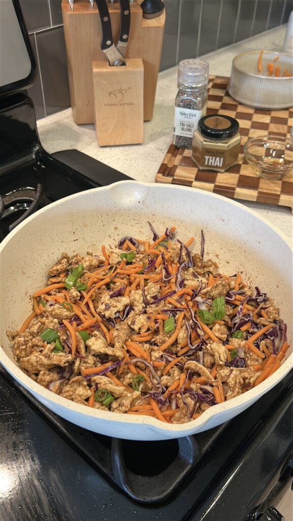 adding cabbage and carrots to Thai chicken lettuce wrap filling