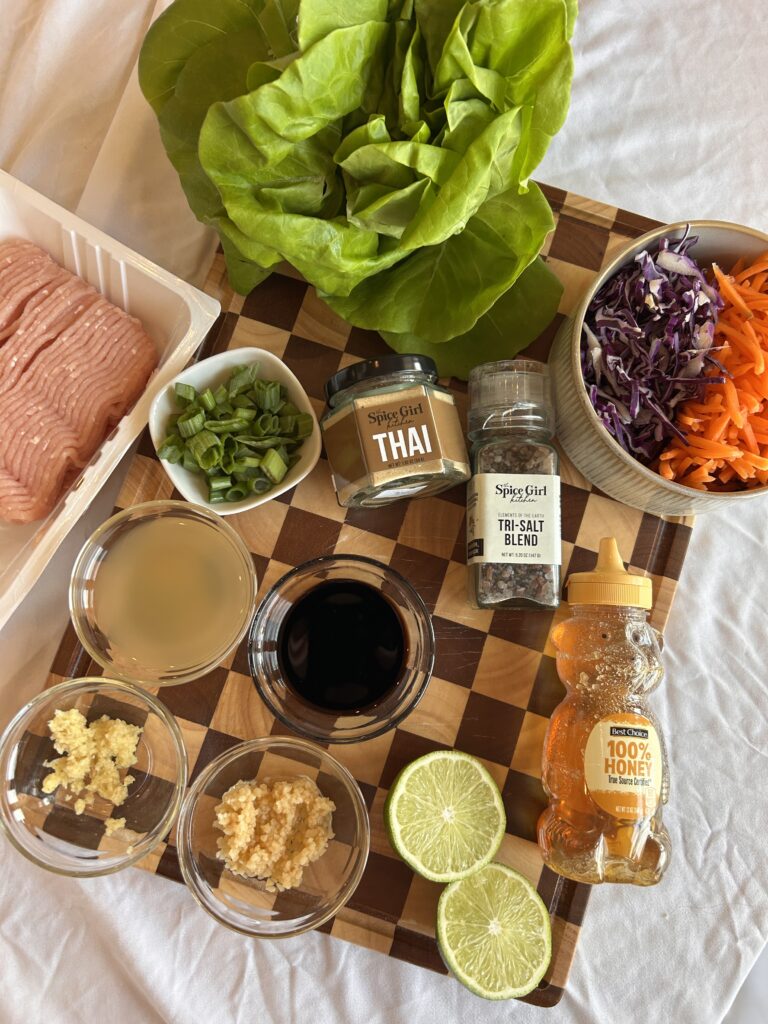 ingredients for Thai chicken lettuce wraps including ground chicken, cabbage, carrots, garlic, ginger, and lettuce