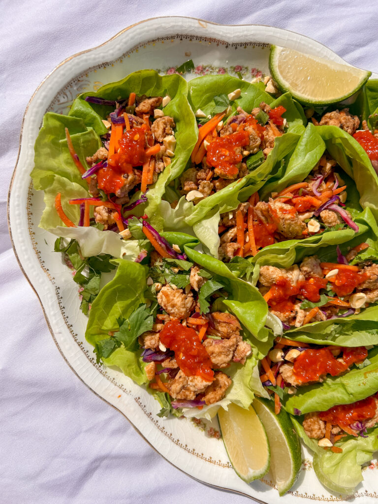 serving Thai chicken lettuce wraps with lime wedges and cilantro