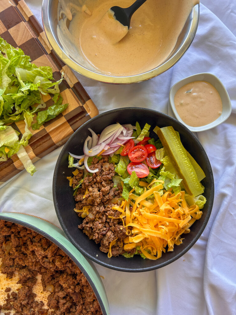 Assembling loaded cheeseburger bowls with toppings