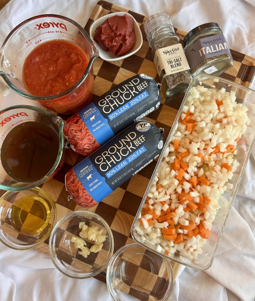 Ingredients for Instant Pot Bolognese sauce including ground beef, crushed tomatoes, carrots, celery, and Italian seasoning