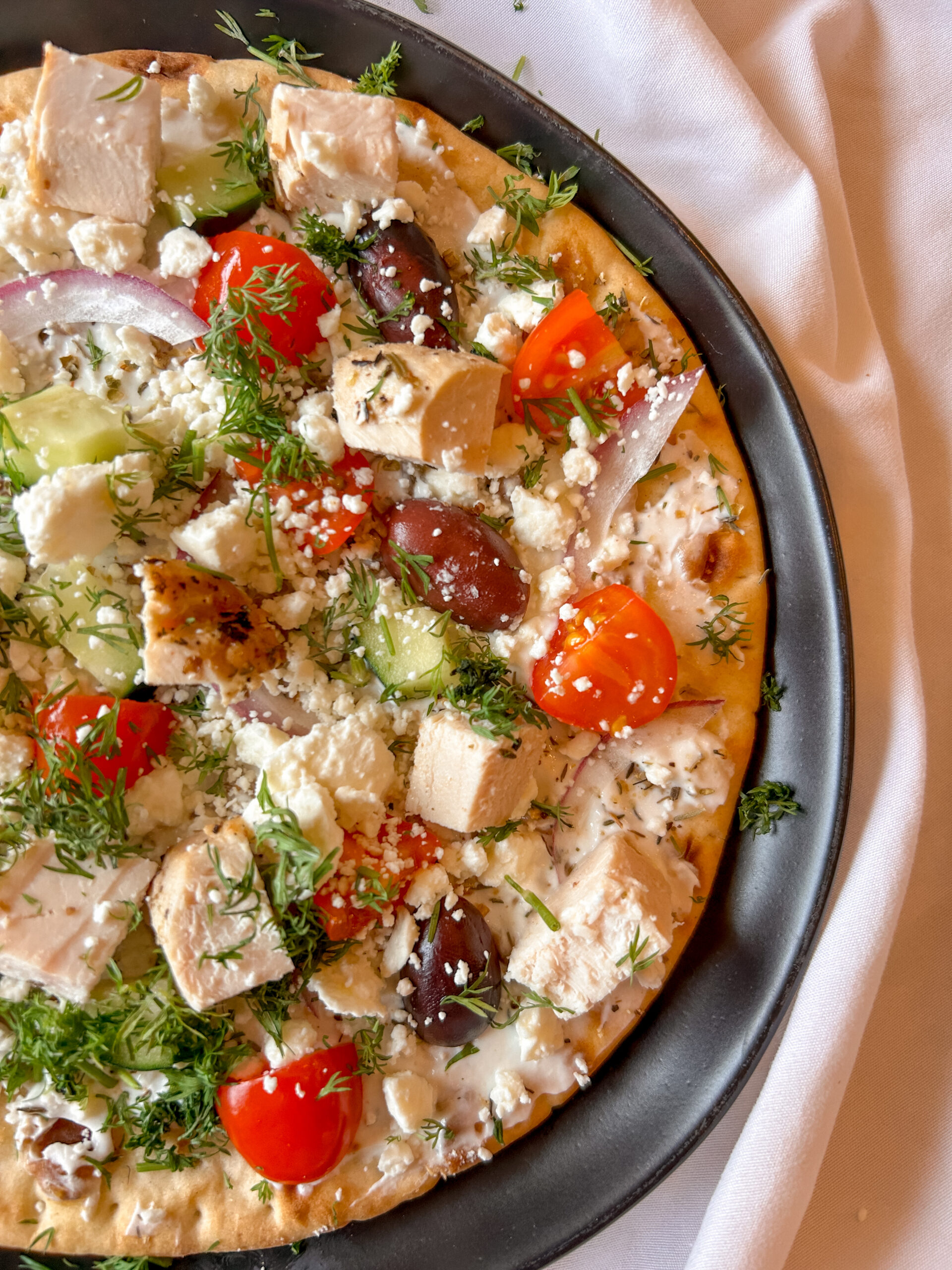 close up of mediterranean flatbread showing yogurt sauce, feta, and fresh toppings