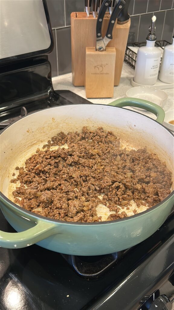 Seasoned cheeseburger meat with Okie Rub cooking in skillet