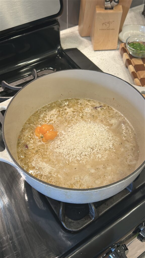 Long grain rice being added to coconut milk and kidney bean mixture