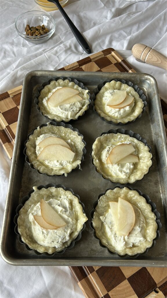 Goat cheese tartlets assembled with pear slices before baking