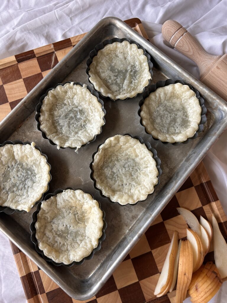 Blind baked puff pastry tart shells in tart pans ready for filling
