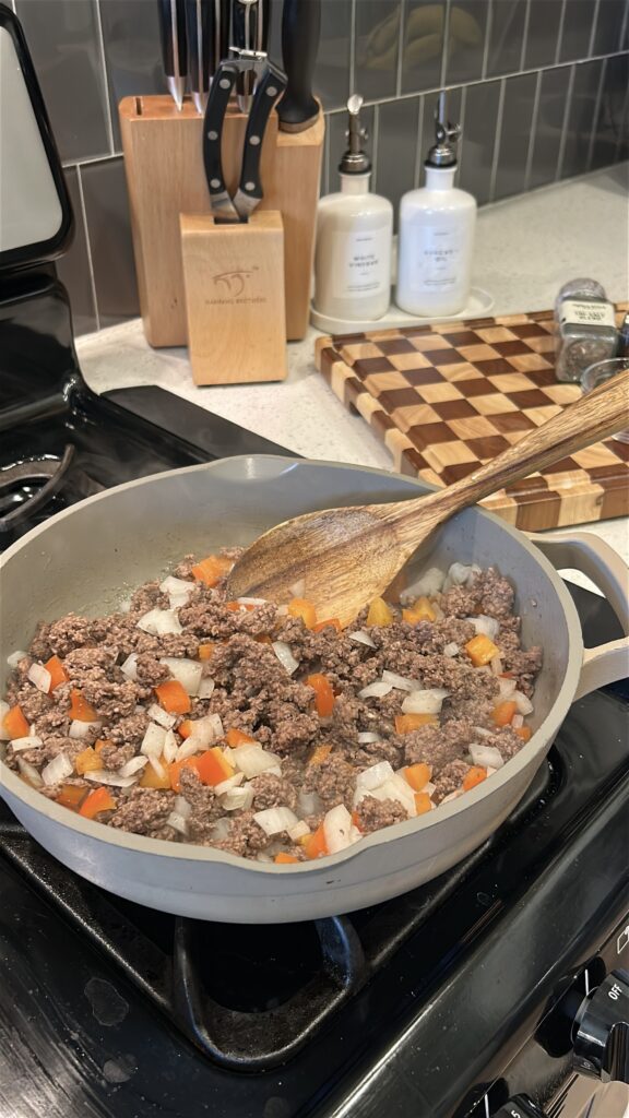 Ground beef browning with onion and bell pepper for slow cooker cowboy casserole